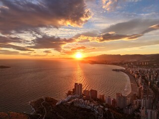 sunset casts striking shadows over serene bay with reflective orange light and urban outlines © Nataliia