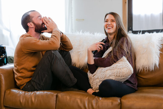 Cute Brunette Couple Sit Together on Couch and Laugh Together