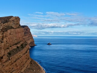 Obraz premium Isolation among high rocks and calm waters, Lonely artwork situated on jagged cliffs over peaceful ocean