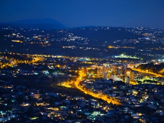 Obraz premium Night highway panorama. Night aerial view showcasing glowing highway alongside coastal hills and sea