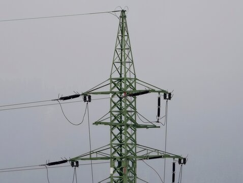 Detailed view of electrical towers with ceramic insulators under dark overcast weather conditions