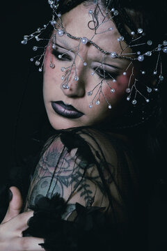 Editorial portrait of a goth woman with a tiara on her face 