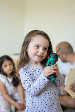 Little girl holding a drill for assembling furniture
