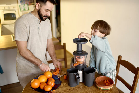 son helps his father make juice in the kitchen