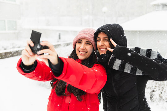 Mother & daughter taking selfie under the snow