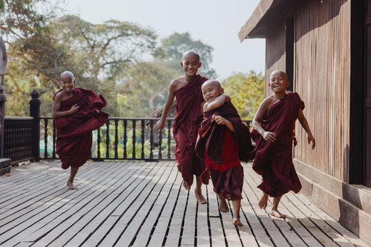 Joyful young monks running on wooden bridge