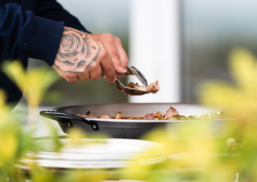 Chef adding ingredients to pan in kitchen