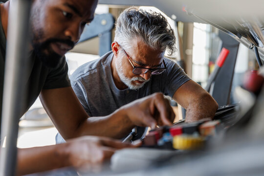 Diverse mechanic repairing car at garage