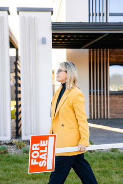 A woman removes the "for sale" sign
