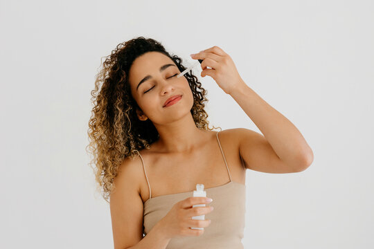 Model applying beauty product on face with dropper