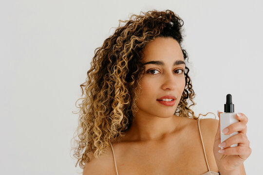 Woman displaying body care oil in dropper bottle