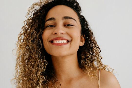 Cheerful curly haired woman with toothy smile
