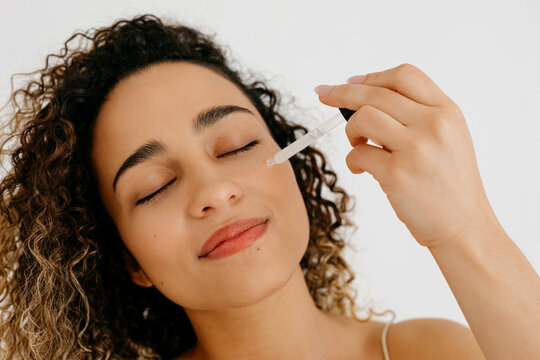 Dreamy model applying serum on face with applicator