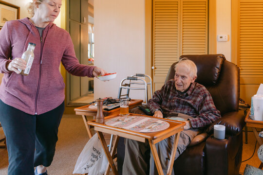 caregiver helping elderly man getting ready for dinner