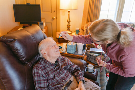 caregiver helping elderly man with eyedrops. 