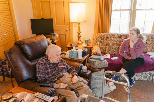caregiver sitting with senior citizen in his home 