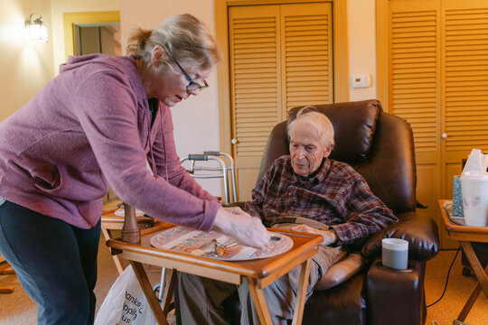 caregiver helping elderly man getting ready for dinner