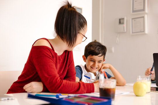 Aunt helping young boy with homework at kitchen table