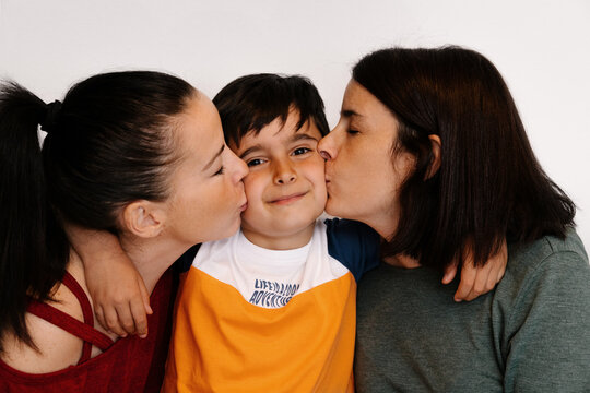 Young women kissing a happy child on cheeks