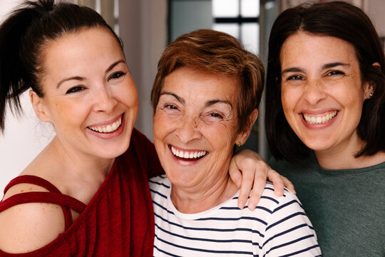 Happy mother with her young daughters smiling together at home