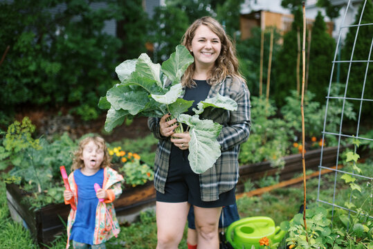 smiling woman and mother standing in garden with kohlrabi in hand