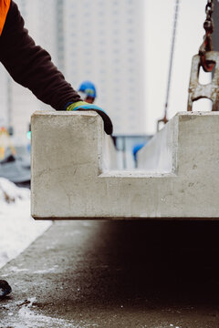 Worker guiding a prefabricated concrete element during precise installation. Manual control ensures accuracy and safety in modern construction projects.