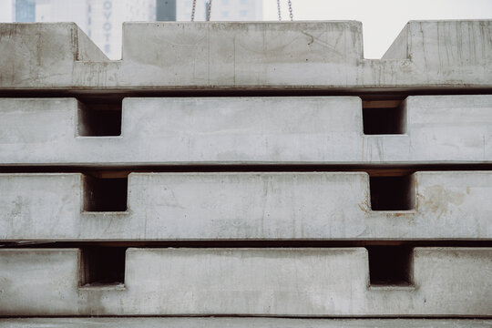 Stack of prefabricated concrete slabs arranged in an industrial storage area. Heavy precast elements used in infrastructure and urban construction projects.