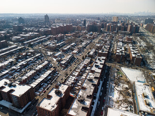 Fototapeta premium Aerial view showing forest hills, queens, new york, during winter, with residential buildings and houses featuring snow covered rooftops, illustrating urban density and a cold season landscape
