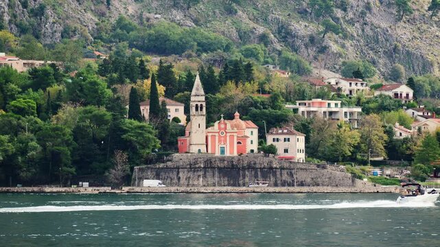 St. Eustace Church sitting on an elevated fortified wall along the Kotor Bay waterfront with mountains