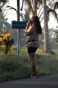 Woman with photo camera takes picture of  nature by "No Hunting" sign