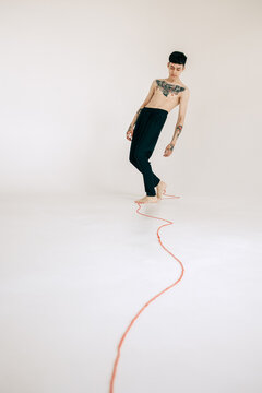 Young Man With Tattoo Following Red String Indoors