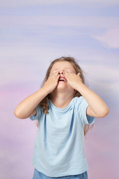 Happy child covering eyes while playing hide and seek in studio