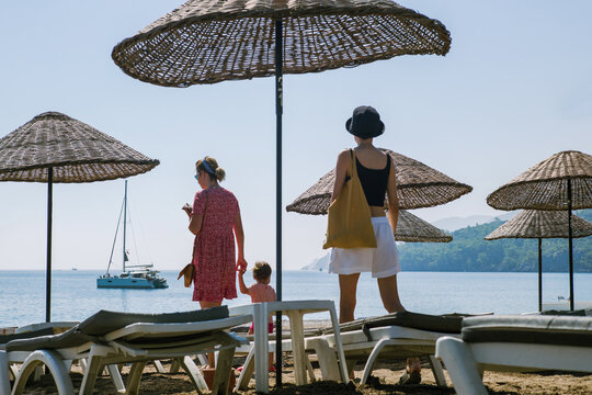 Friends looking for a free place on the beach under sun umbrellas