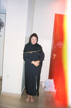Woman in Traditional Black Abaya Standing Indoors with Modest Decor