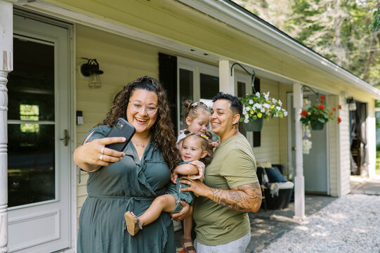 smiling lgbtq family taking selfie with key and new house