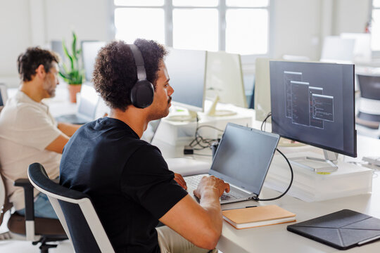 Focused software developer wearing headphones working on computer