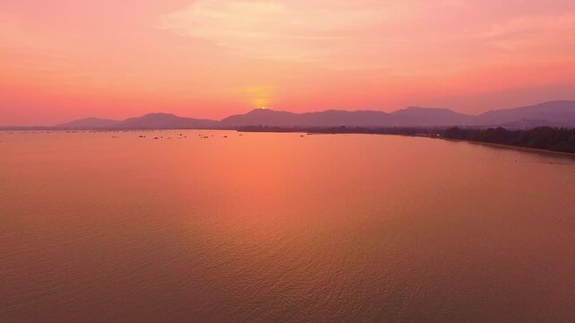 Above the mountain range, a sweet and serene sunset sky unfolds clouds tinged with rose and lavender hues, glowing softly as daylight gives way to the tender calm of evening.