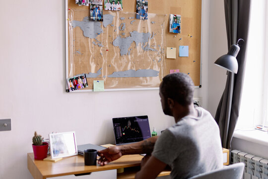 Man taking cup with coffee or tea during watching graph on laptop