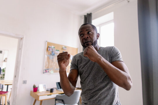 Concentrated bearded man training fighting boxing in blurred room