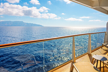 Fototapeta premium A large private stateroom suite balcony aboard a large cruise liner as it passes by islands in the Mediterranean Sea.