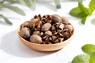 Obraz premium A wooden bowl filled with nutmeg seeds on a white surface