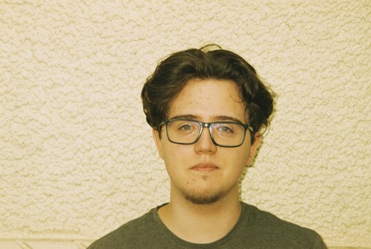 Portrait of man with glasses against a textured wall.