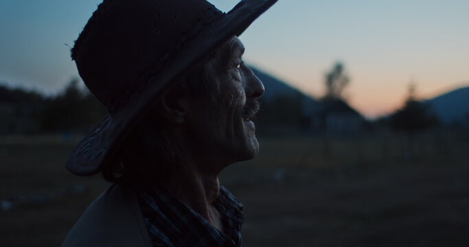 Man with a hat watches sunset on a mountain