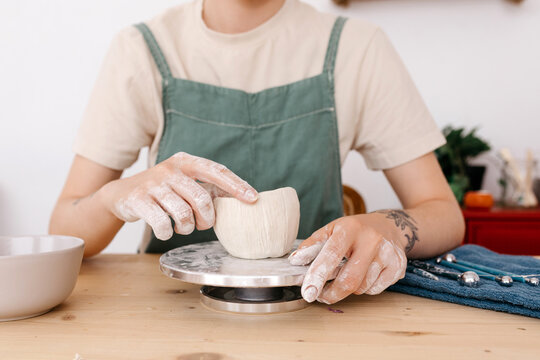 Crop artisan shaping clay on wheel