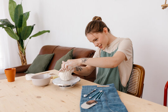 Optimist woman making ceramic pottery in workroom