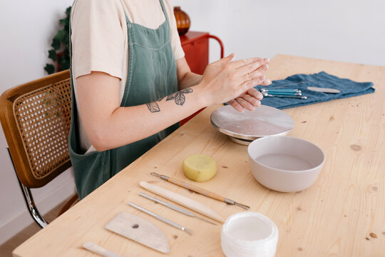Craftswoman pressing clay with hands