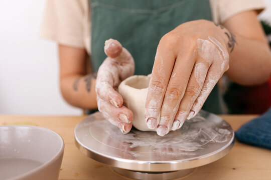 Crop woman shaping clay bowl rim