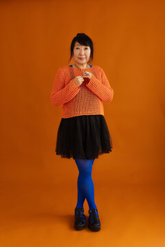 Confident woman in stylish outfit standing in studio