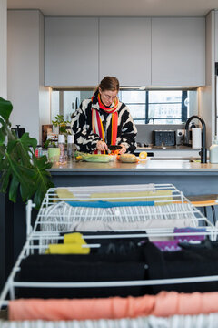 A woman preparing vegetables in modern kitchen setting.