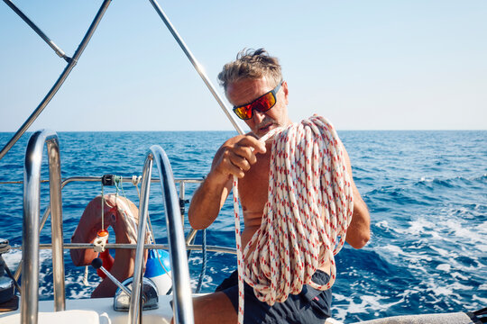 Sailor winds the rope on the deck